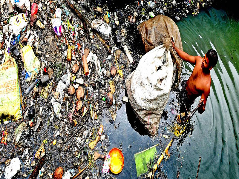 © C-HED/Baiju Koduvally Un recogedor de basura se sumerge hasta la cintura en el agua de un canal de Kochi (India).